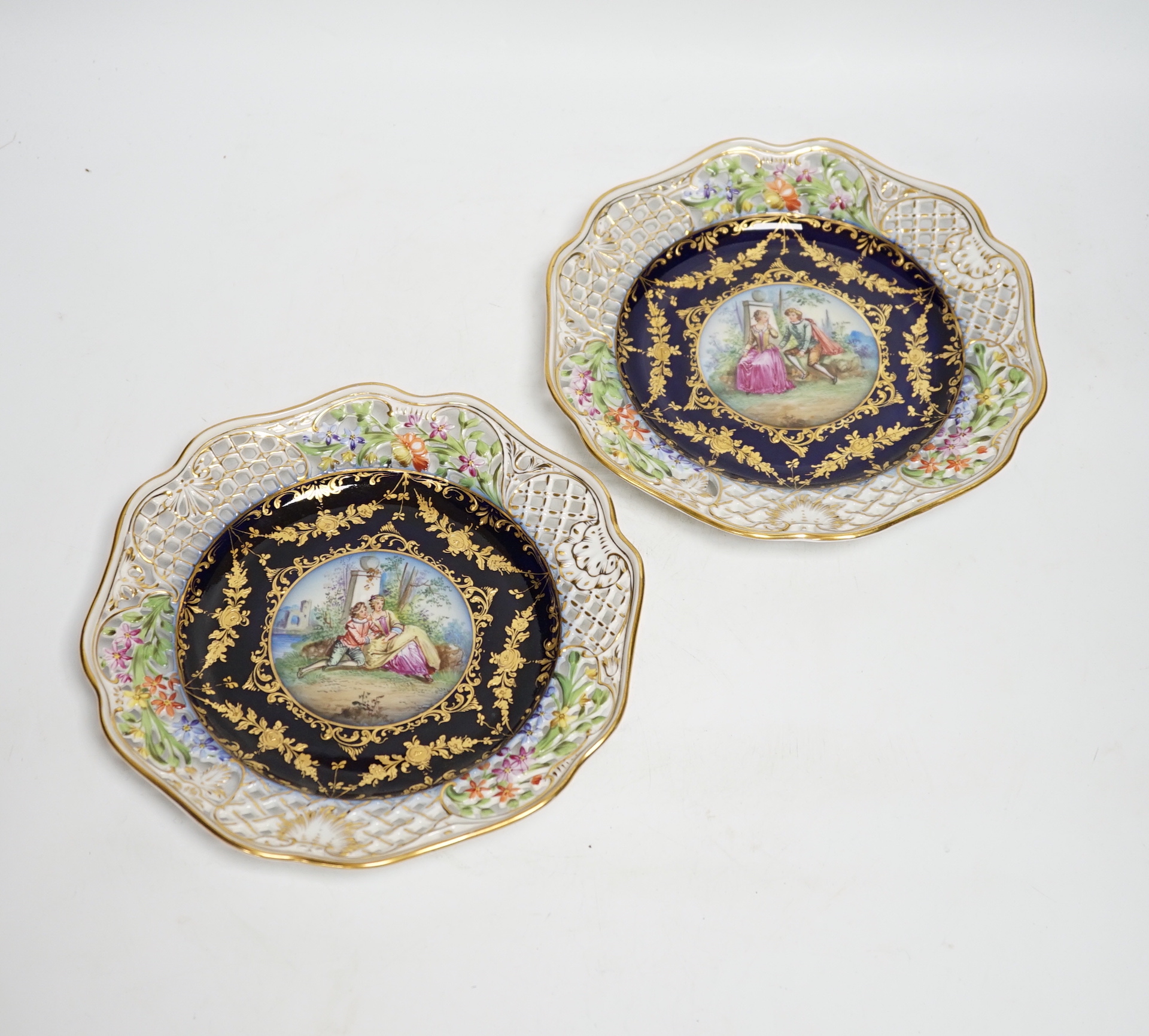A pair of Dresden blue cabinet plates decorated with central cartouche of lovers, 22cm diameter